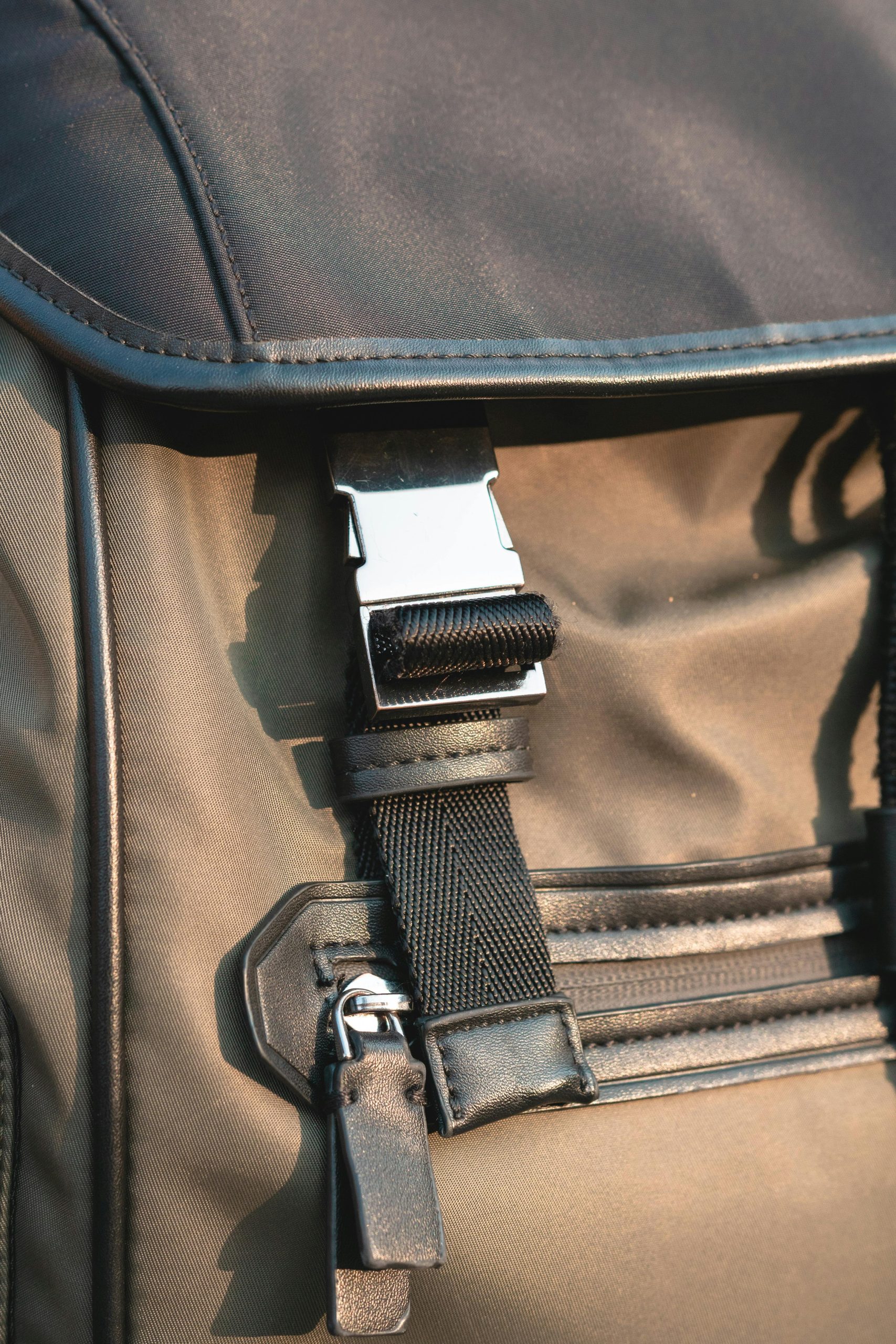 A close-up view of the metal buckle and zipper slider of a black backpack