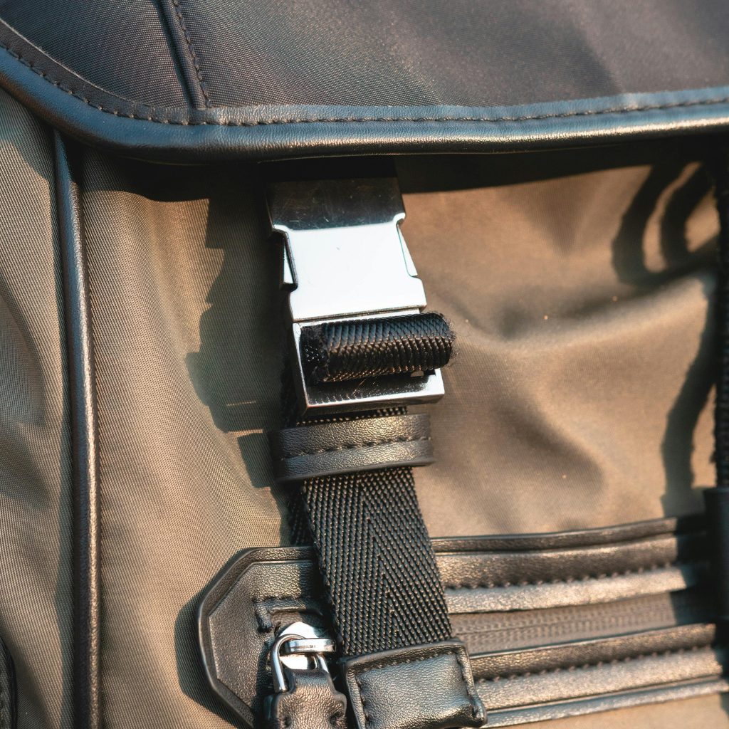 A close-up view of the metal buckle and zipper slider of a black backpack